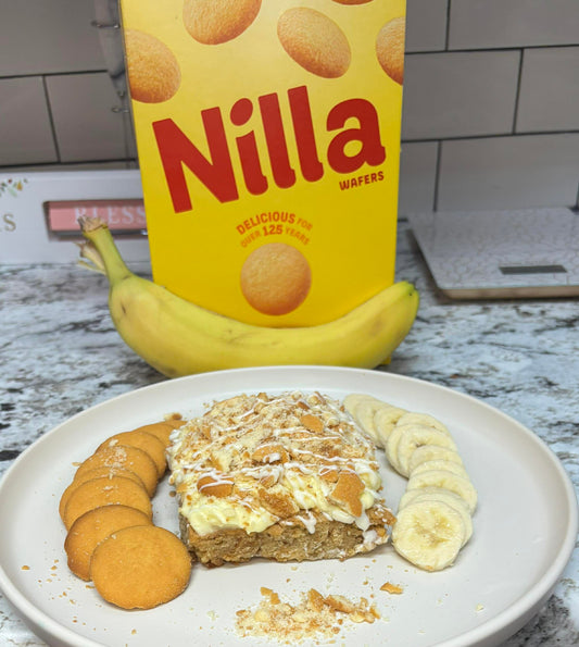 Nilla wafers, banana, and dessert on a plate with a box of Nilla wafers in the background.